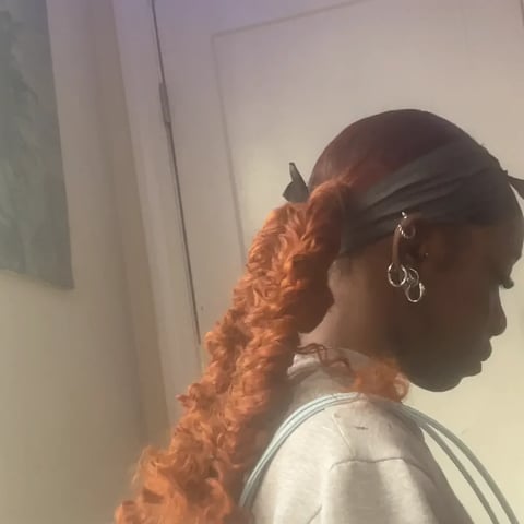 Person with orange curly hair in a ponytail
